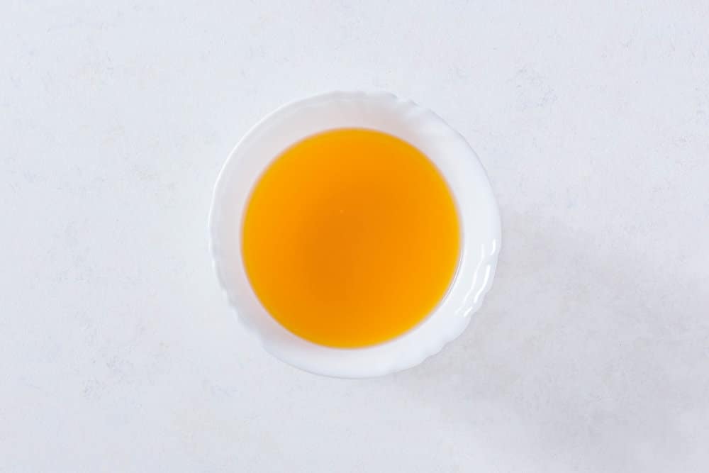 Jello with water mixed in a white bowl for mandarin mousse cake.