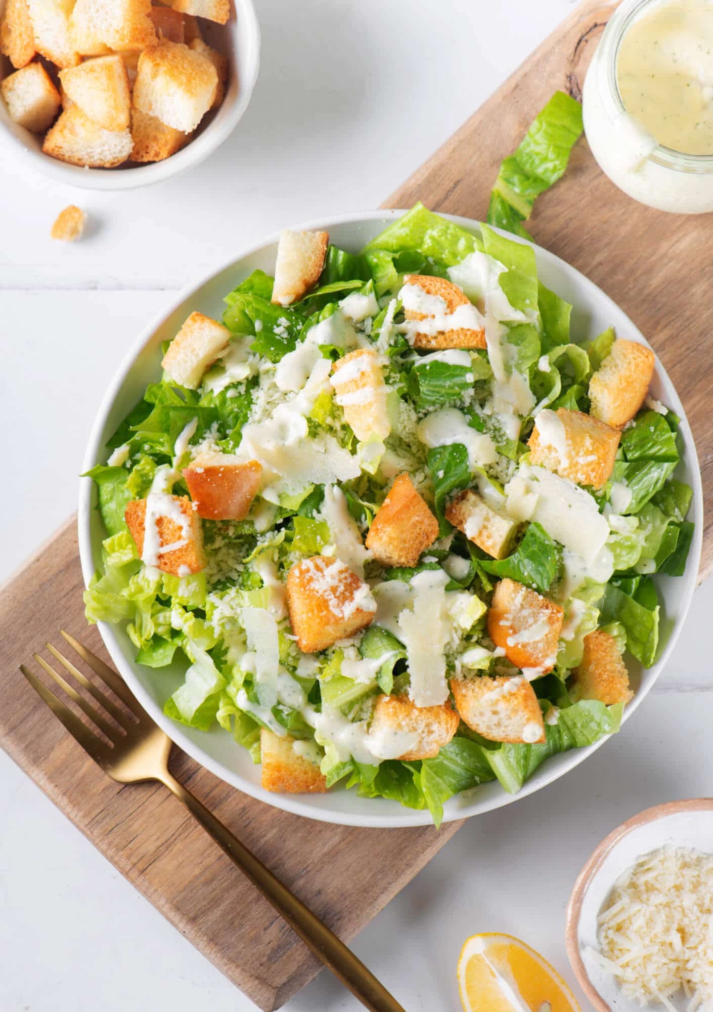 Low-Calorie Caesar Salad With Caesar Dressing caesar-dressing-in-a-white-bowl-with-a-fork-on-a-wooden-board