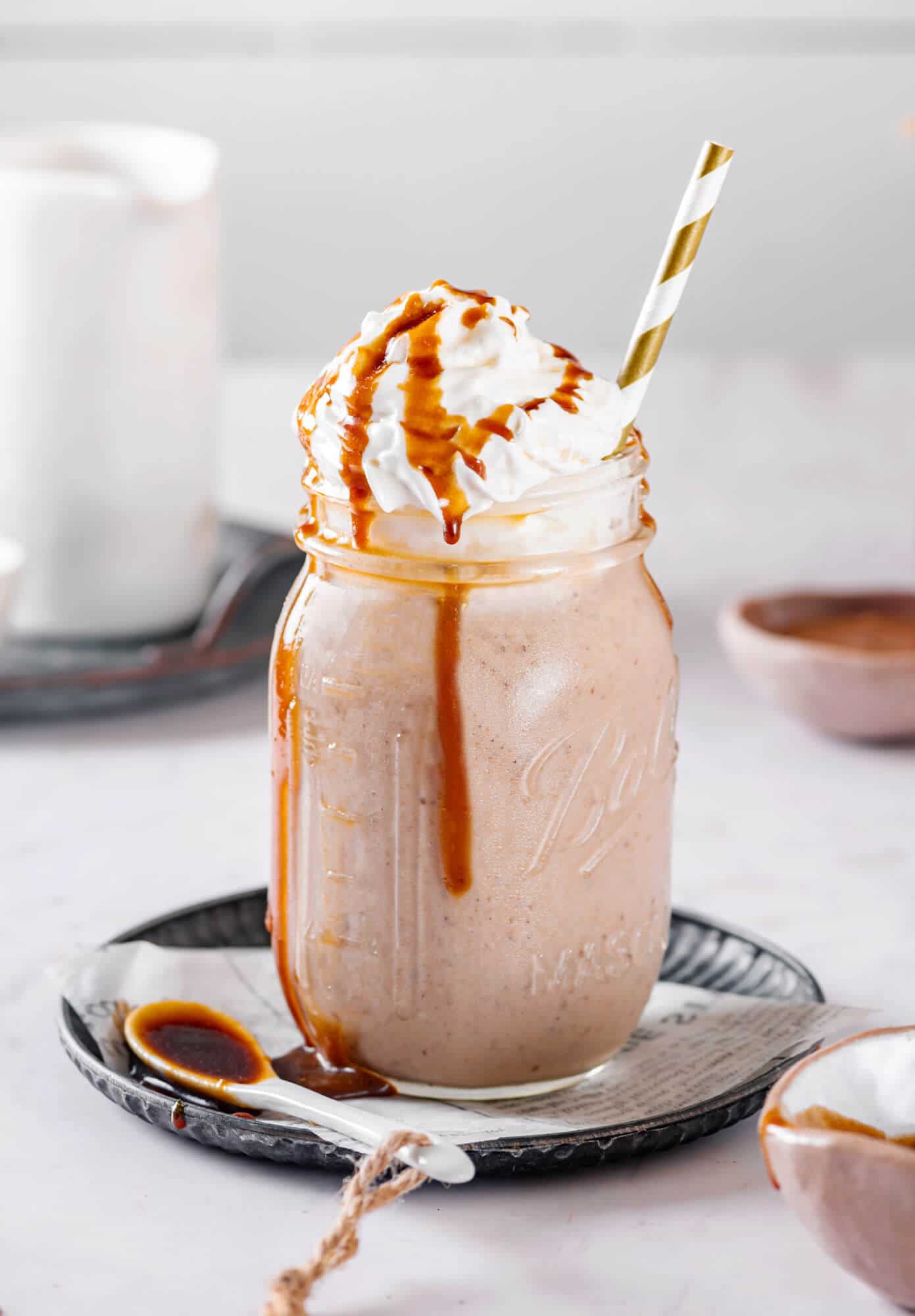 A Healthy Caramel Smoothie Recipe healthy caramel smoothie in a mason jar, with cream and caramel drizzle.