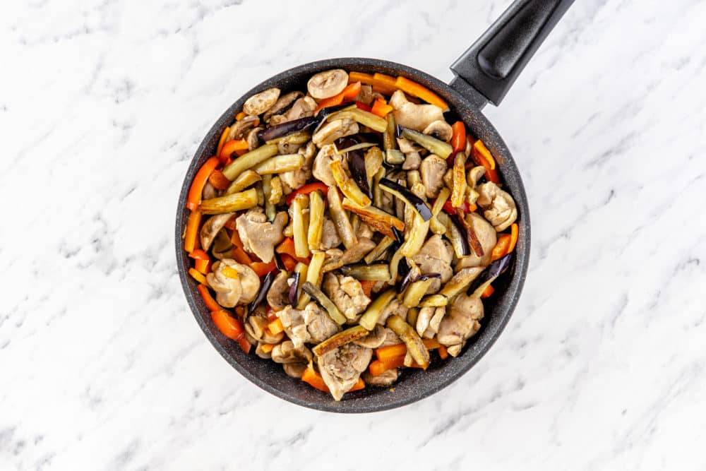 a black skillet with veggies and chicken in it.