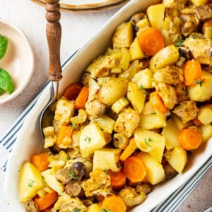roasted chicken and veggies in a white bowl with a serving spoon.