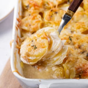 scalloped-potatoes-in-baking-dish-on-wooden-board-with-a-spoon