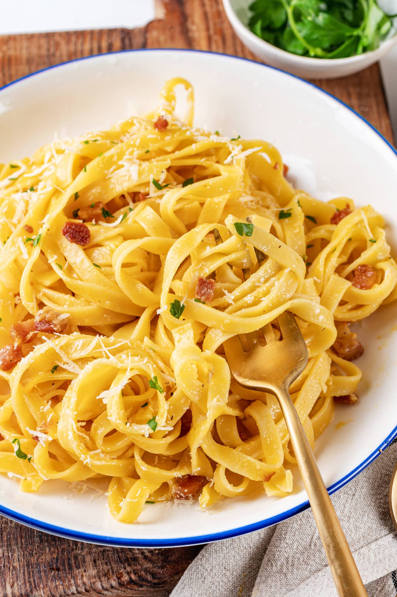 Easy Pasta Carbonara Recipe with Pancetta Pasta carbonara in a white bowl with a gold fork.