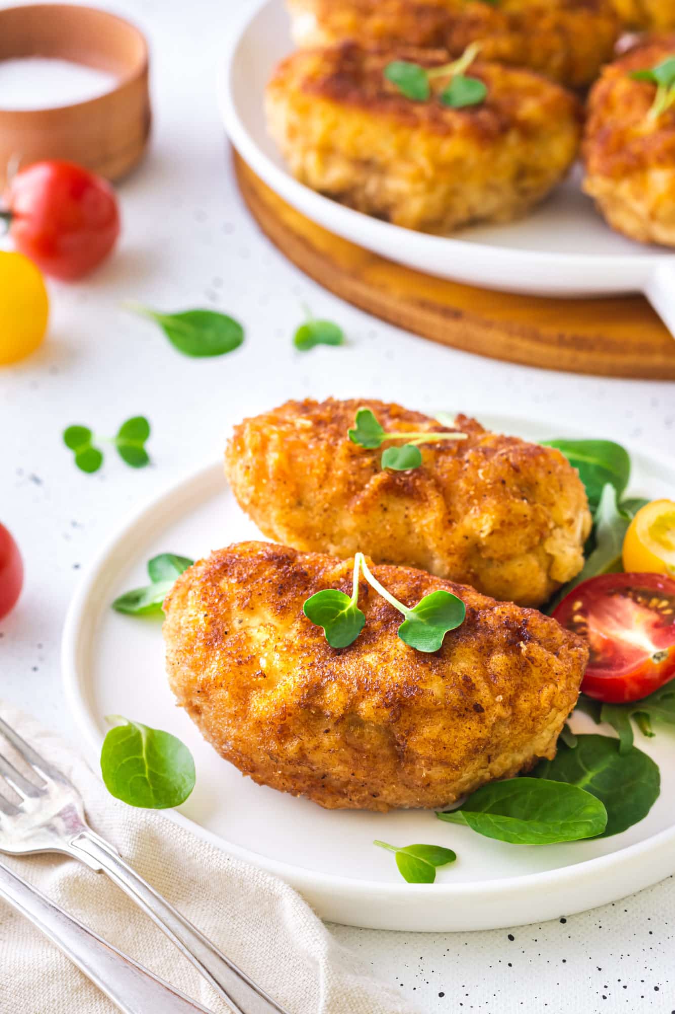 Simple Butter Stuffed Chicken Breast a white plate with prepared stuffed chicken and microgreens.