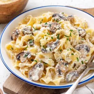 A bowl of mushroom alfredo pasta with a fork on the side.