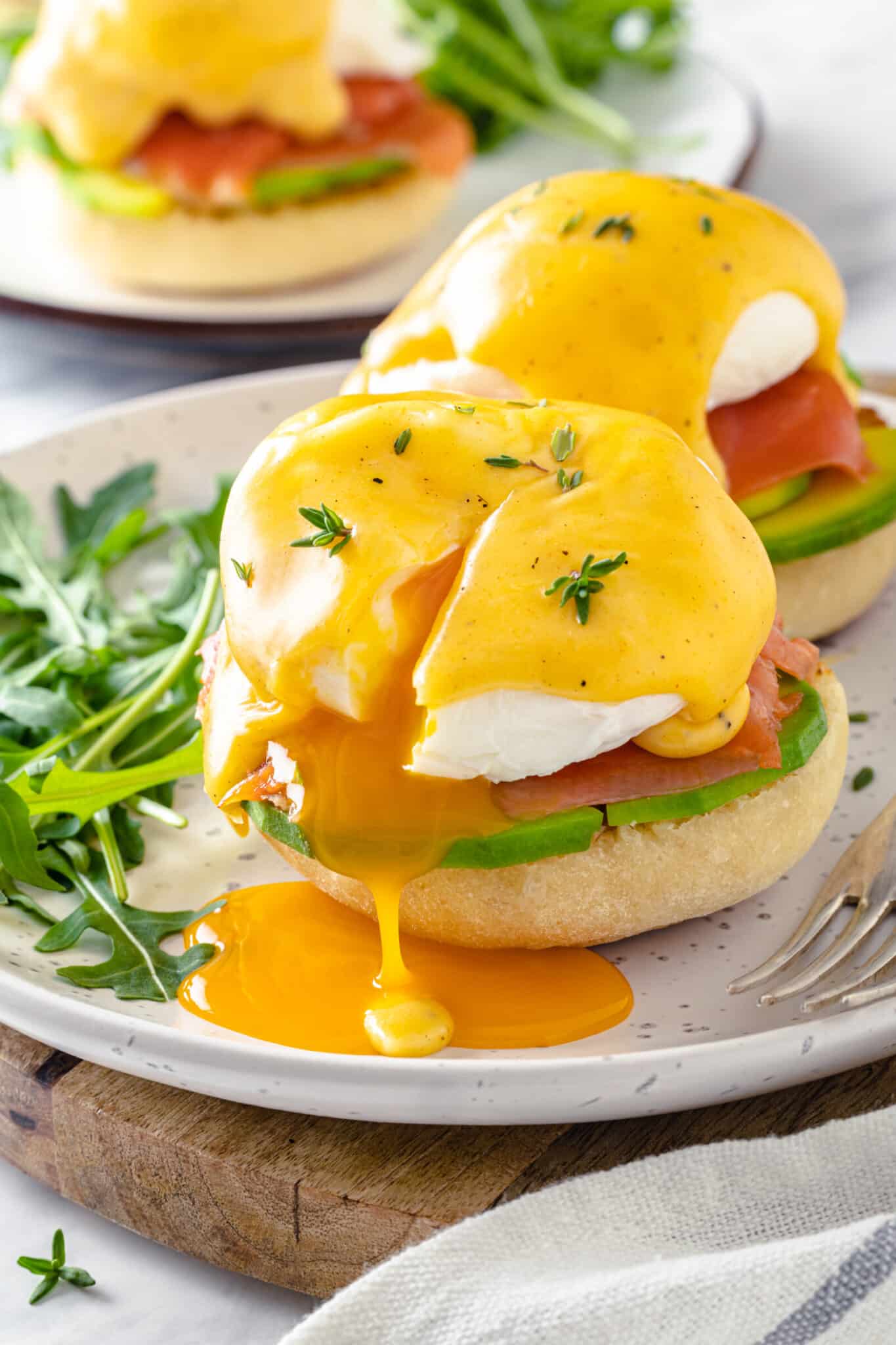 Smoked Salmon Eggs Benedict a white plate serving smoked salmon eggs benedict with the poached egg leaking yolk