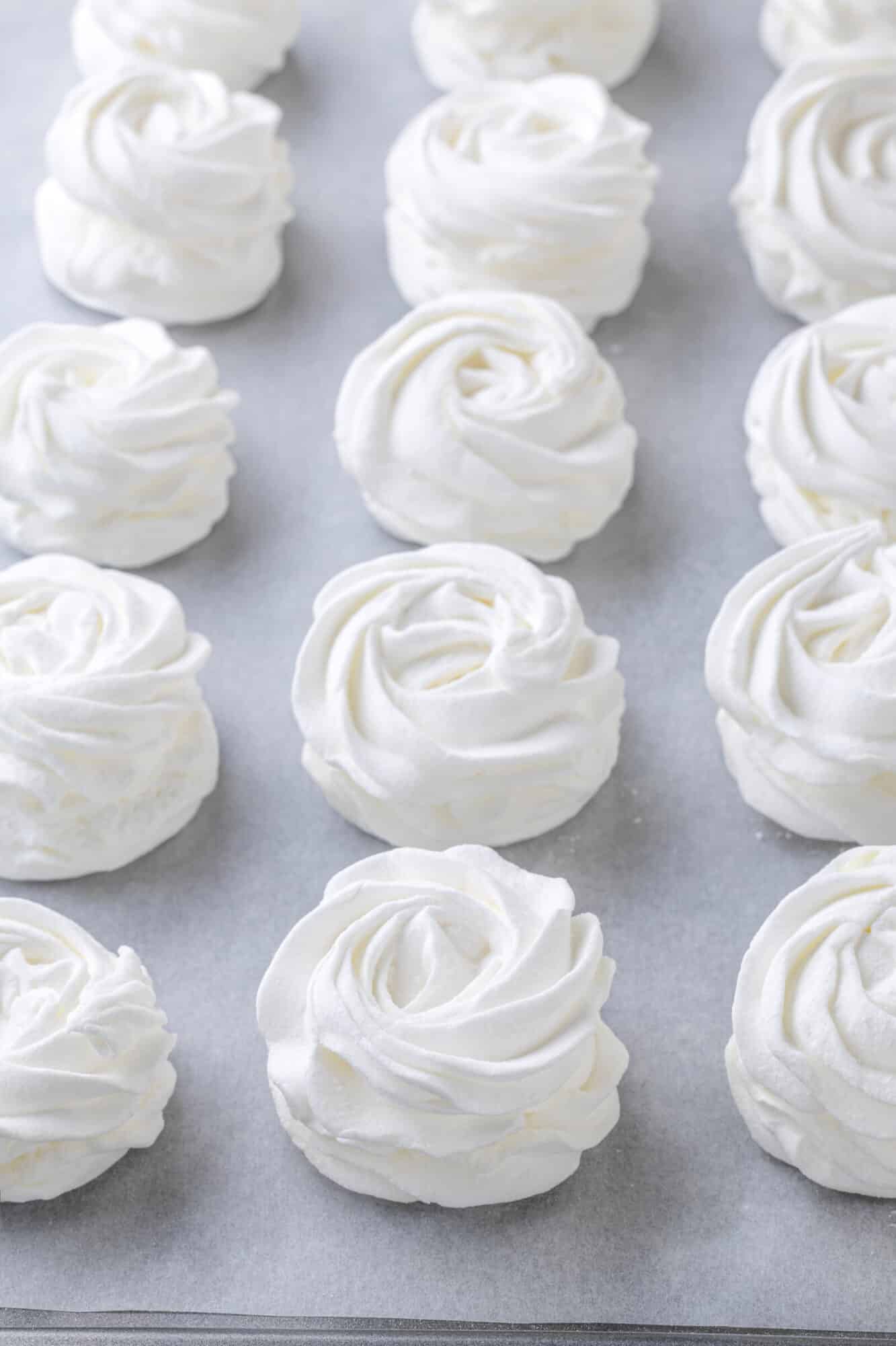 Marshmallows set on a baking tray with parchment paper.