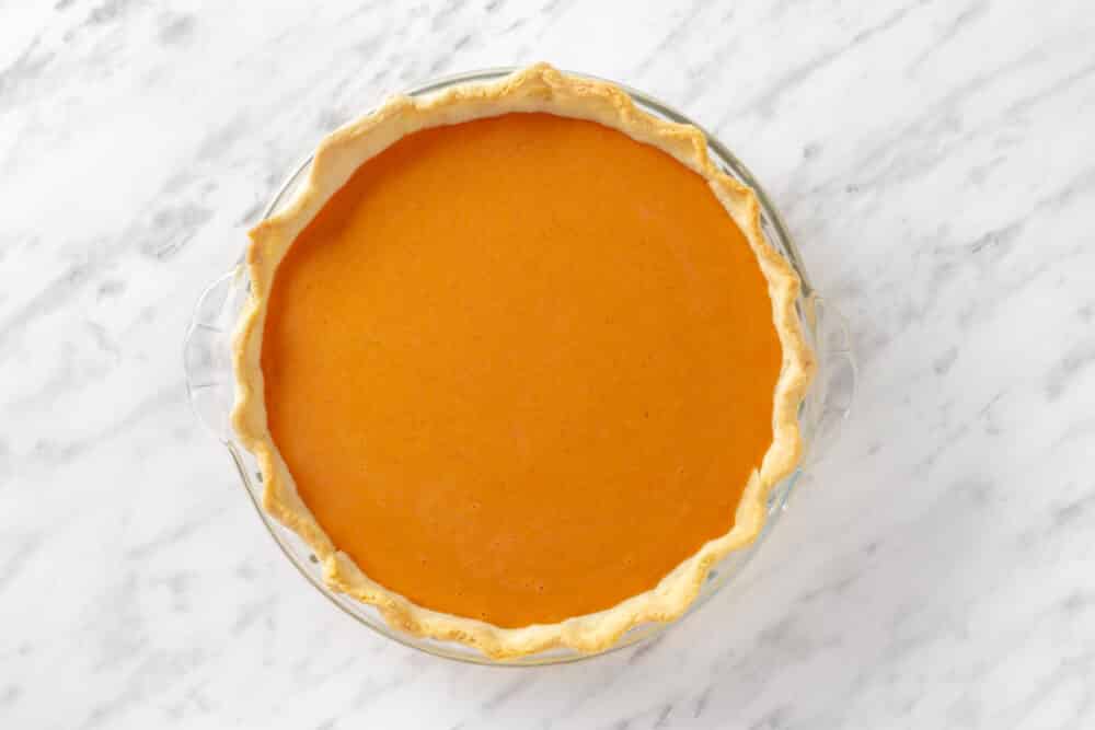 Poured pie filling into baked pie crust in a glass dish.