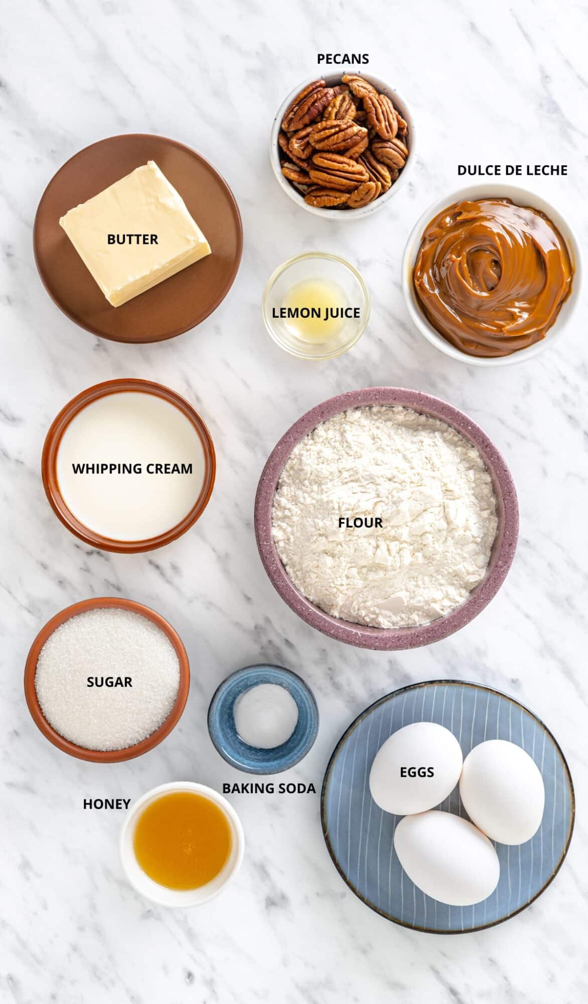 Honey cake ingredients- sugar, flour, dulce de leche, lemon juice, baking soda, whipping cream, pecans, honey, butter, and eggs.